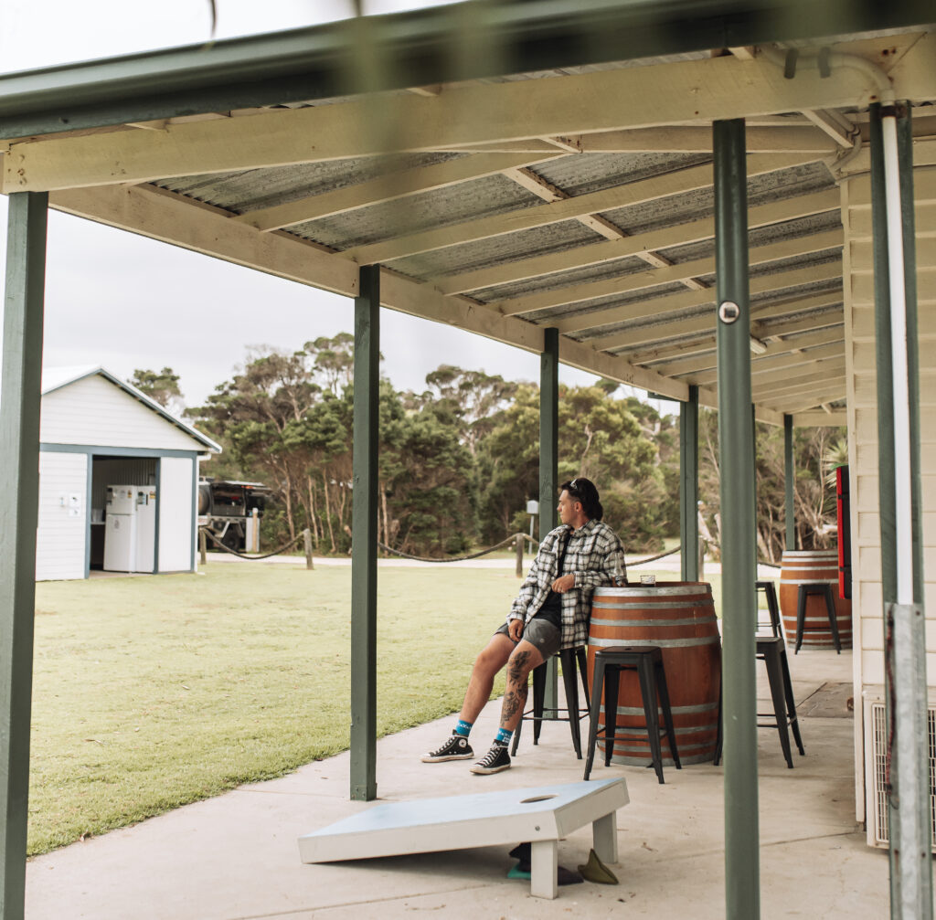 Man sitting on a bar stool under a pergola at caravan park